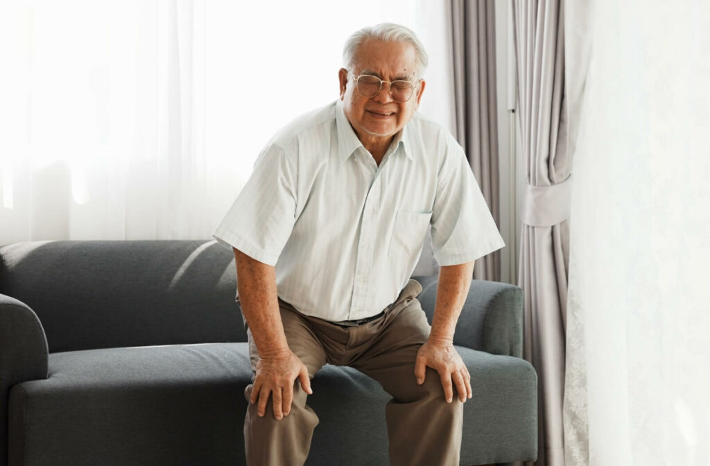 An older man struggles to stand, holding his knees in pain, showing a common challenge of aging.