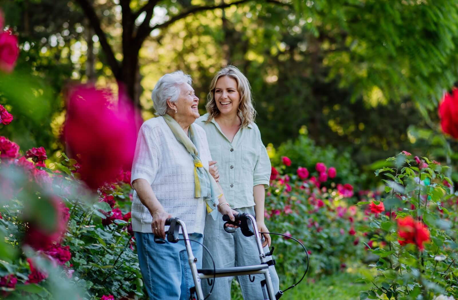 a younger woman and her senior mother with mobility issues walk through a park