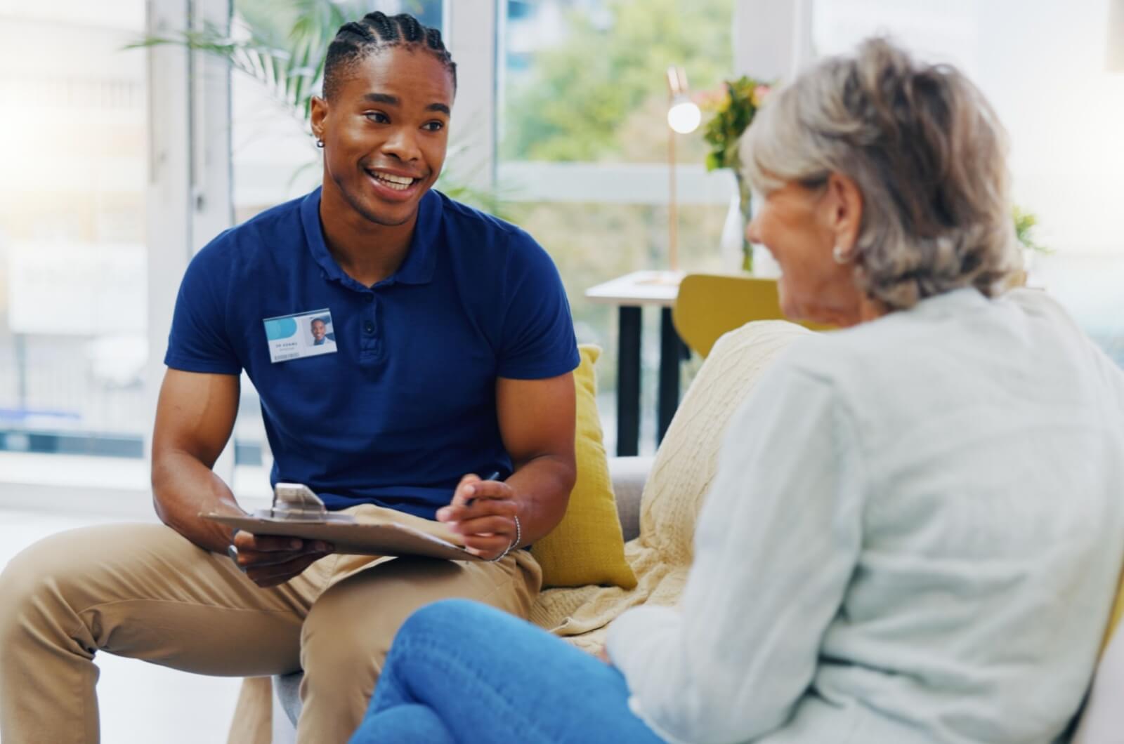 A professional staff member and an older adult sitting and having.a conversation during an assisted living community tour.