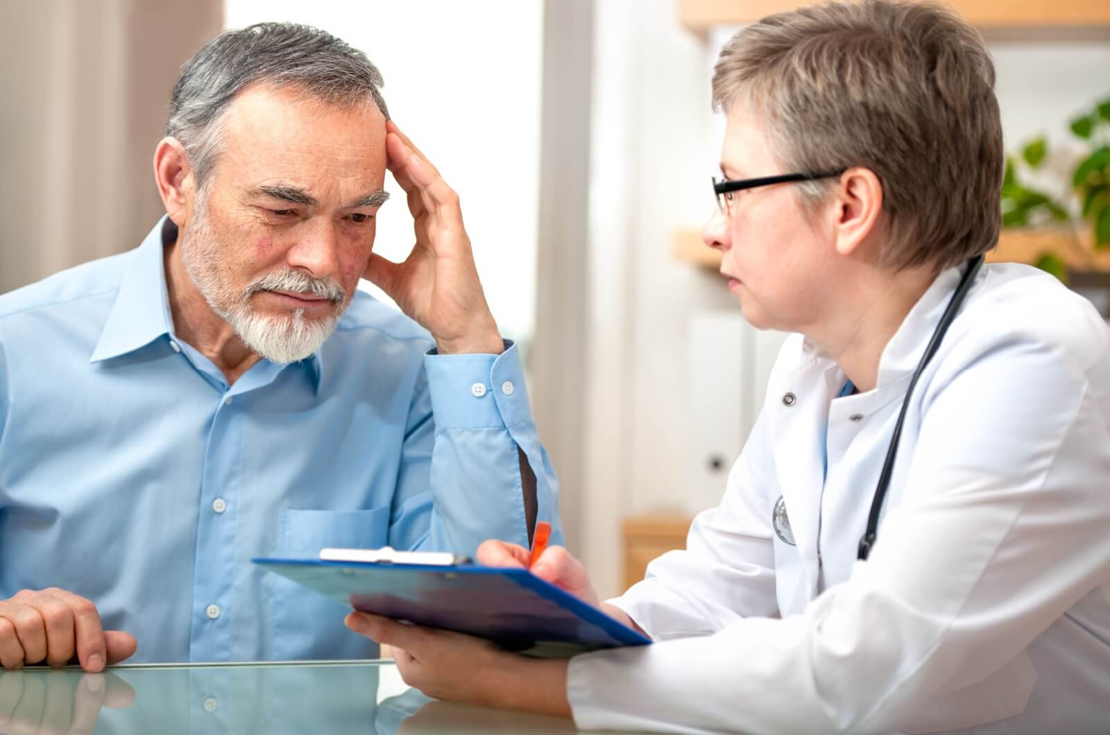 A concerned parent sitting next to a healthcare professional receiving a dementia diagnosis.