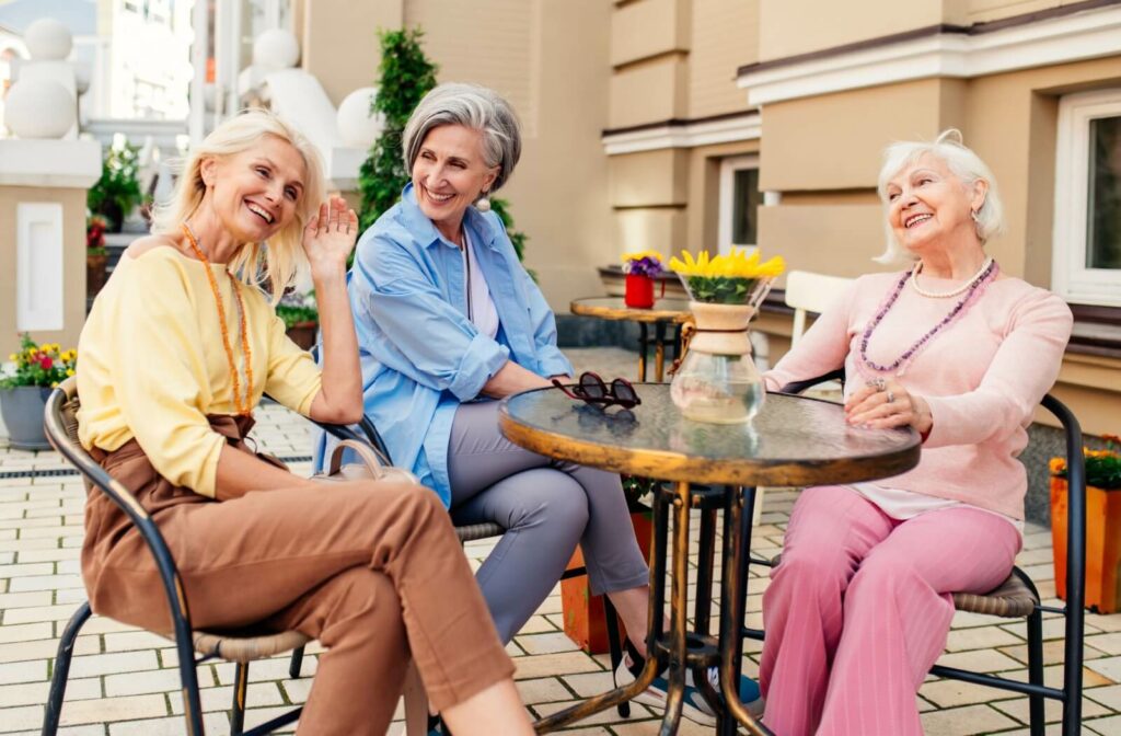 A smiling group of older adults sitting outside at a table.