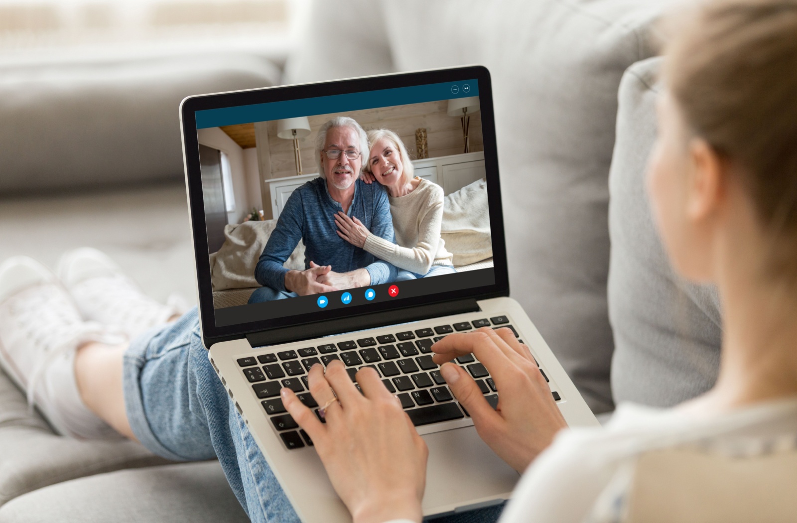An over-the-shoulder shot of an adult child video calling their older parents.