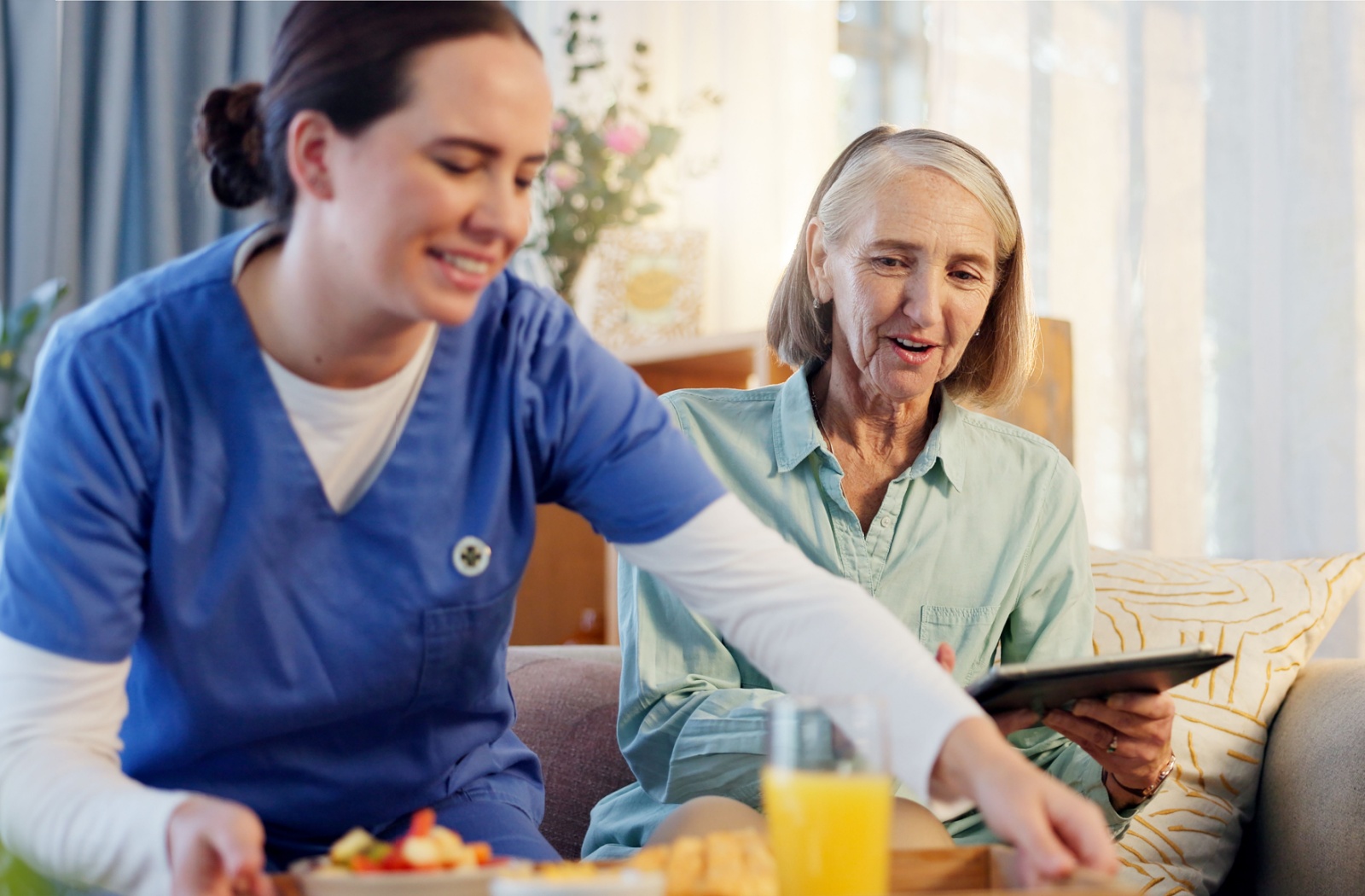 A caregiver serves breakfast to an assisted living resident.